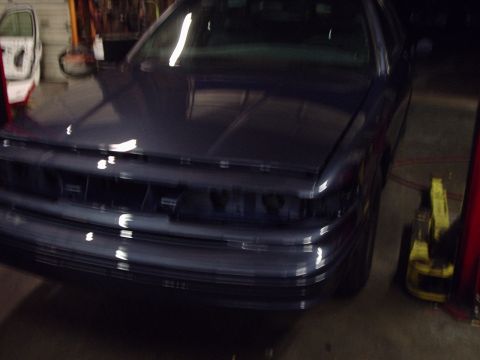 1996 Ford Crown Victoria - A dark blue sedan is shown from the front in a garage, with its headlights and grille removed.