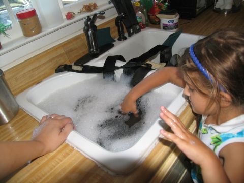 1978 Ford Bronco - A child helps wash seat belts in a kitchen sink, surrounded by soap suds.