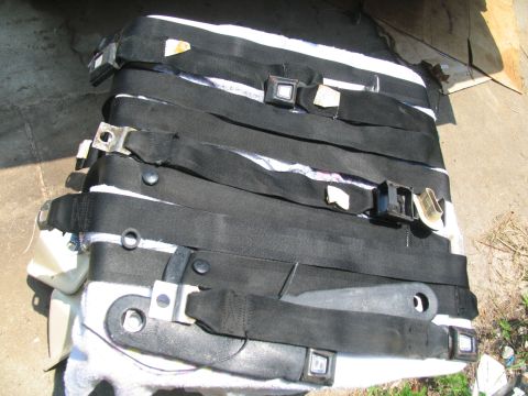 1978 Ford Bronco - Multiple black seat belts are piled on top of each other, showing their buckles and mounting points.