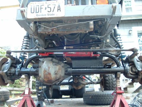 1991 Ford Bronco - The front suspension and steering system of a modified off-road vehicle are visible, supported by jack stands.