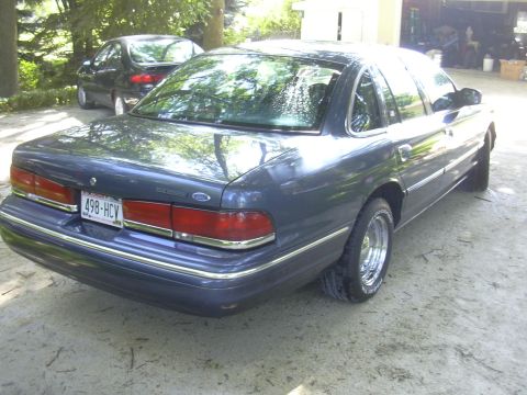 1996 Ford Crown Victoria - Rear view of a 1996 Ford Crown Victoria with chrome wheels, parked outdoors.