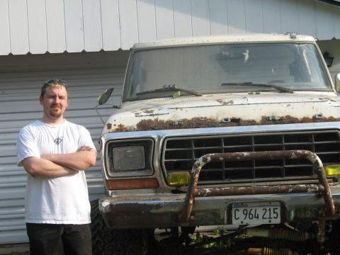 1978 Ford Bronco - A man poses with a weathered Ford pickup truck, showing significant rust and a custom front bumper.