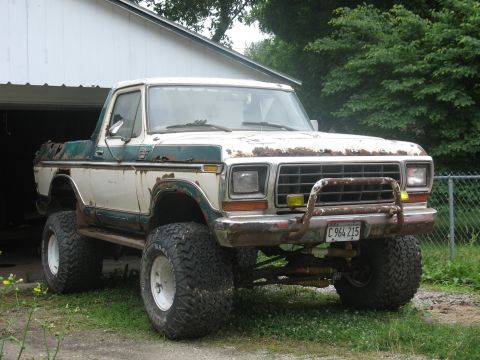 1978 Ford Bronco - This lifted 1978 Ford Bronco features off-road tires and a prominent push bar, showing signs of wear and tear.