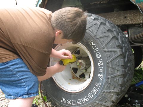 1978 Ford Bronco - A person is shown working on a large tire with "Mickey Thompson" written on the sidewall.