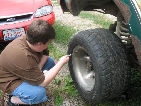 1978 Ford Bronco - A person is shown using a tire gauge to inflate a tire on a vehicle.