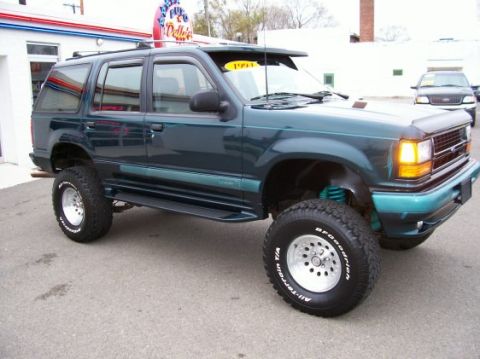 1994 Ford Explorer - This modified SUV is parked in front of a dealership with a '1994' sticker on the visor.