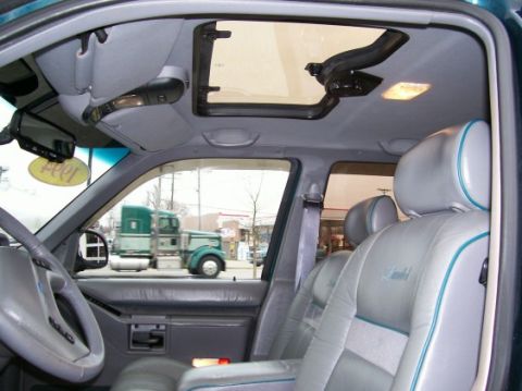 1994 Ford Explorer - The interior of a 1994 Ford Explorer, leather seats and a sunroof, with trucks seen outside.