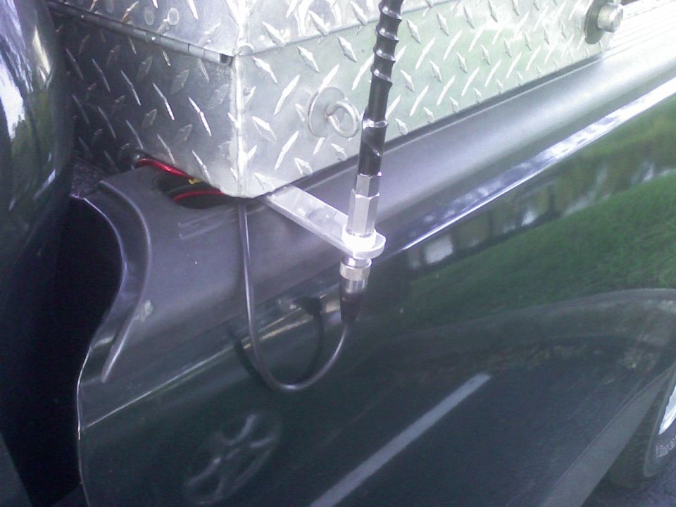 Aluminum diamond-plate toolbox with antenna mount on a truck bed