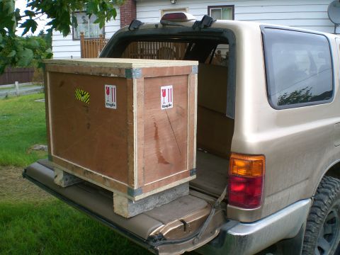 1995 Ford Probe - A large wooden crate is loaded into the back of a gold SUV.