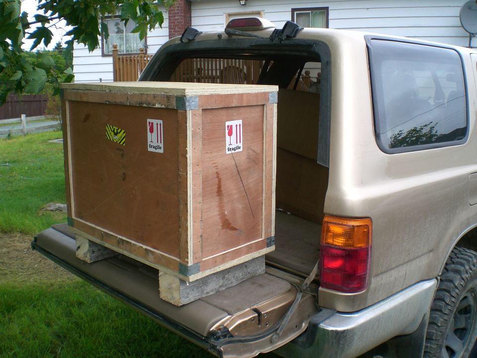 Gold SUV's open tailgate with a large wooden crate inside