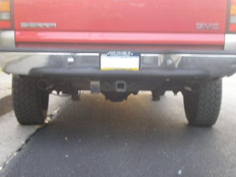 1994 Ford Probe - Rear view of a red GMC Sierra pickup truck, showing the bumper, trailer hitch, and dual exhaust pipes.