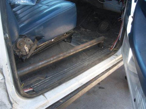 1995 Ford Bronco - The interior of a vehicle shows a roll bar installed along the floor near the driver's seat.