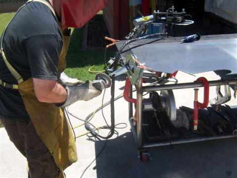 1995 Ford Bronco - A person in a welding mask and apron grinds a piece of metal with an angle grinder.