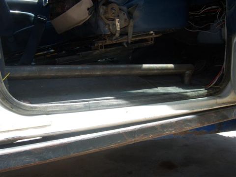 1995 Ford Bronco - The interior of a vehicle shows a roll bar installed near the door, with visible wiring and seat components.