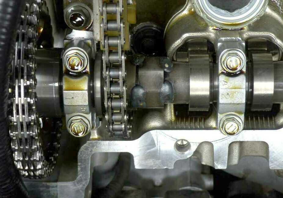 Close-up of camshaft, bearing caps and timing chains inside an aluminum DOHC head