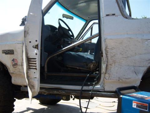 1995 Ford Bronco - Interior view of a white 1995 Ford Bronco, modified with a rollcage and welding equipment nearby.