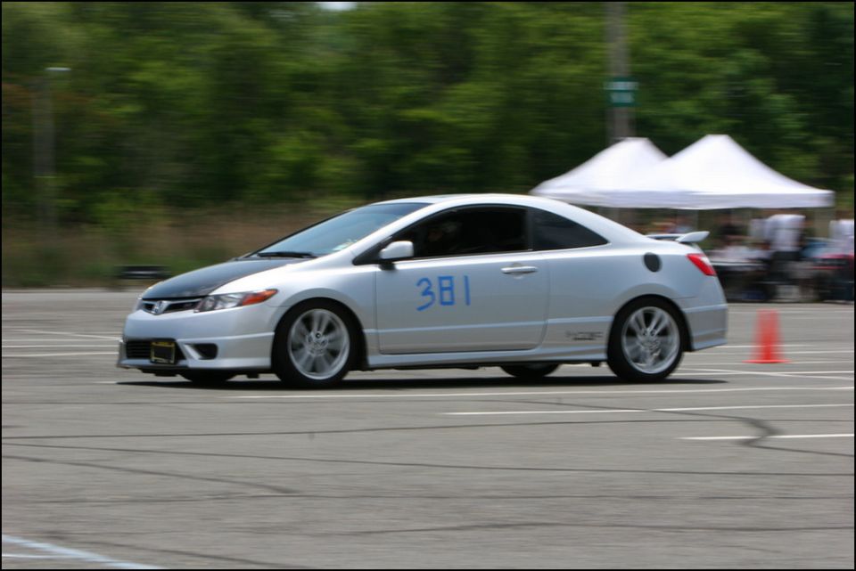 Silver coupe with black hood and blue number 381 on the door, driving on a track