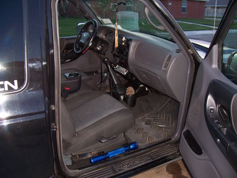 2003 Ford Ranger - The interior of a black 2003 Ford Ranger pickup truck is visible through the open driver's side door.
