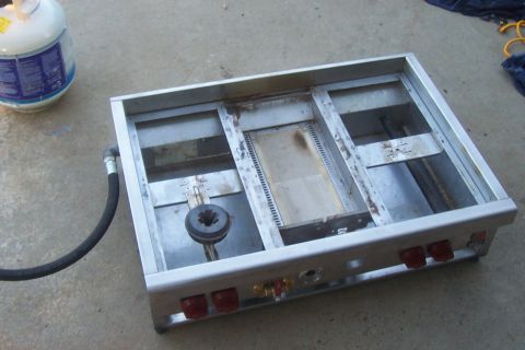 1994 Ford F-150 - A propane camp stove with a burner and hose is shown connected to a propane tank, resting on a concrete surface.