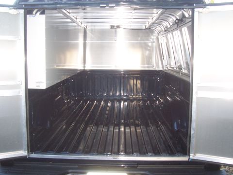 1994 Ford F-150 - The interior of a truck bed is shown with a cap installed, aluminum lining and a black bed liner.