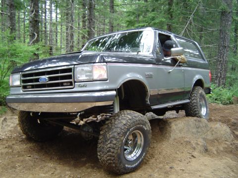 1989 Ford Bronco - This 1989 Ford Bronco is shown off-roading on a dirt trail with lifted suspension and large tires.