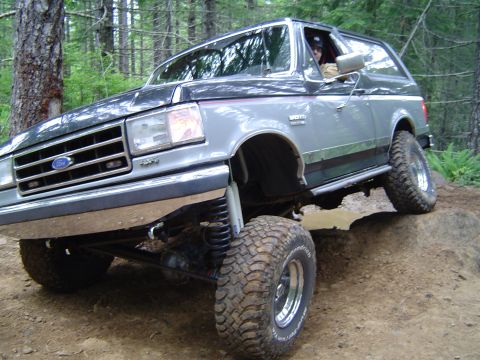 1989 Ford Bronco - This Ford Bronco is navigating a challenging off-road course with large tires and lifted suspension.