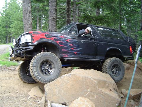 1989 Ford Bronco - This modified Ford Bronco is navigating a challenging rocky terrain on an off-road trail.