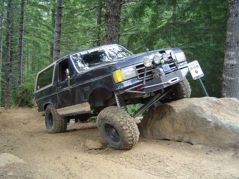 1989 Ford Bronco - This modified SUV navigates a rocky trail with its front tire high in the air.
