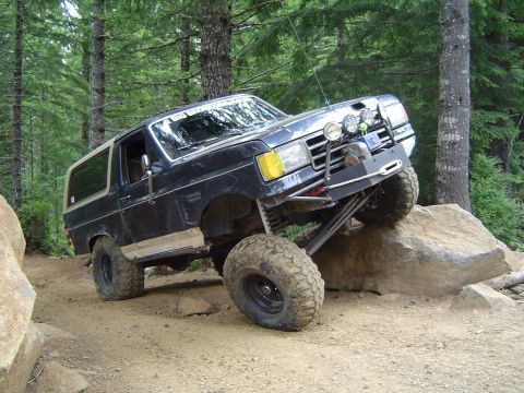 1989 Ford Bronco - Ford Bronco navigates a challenging off-road obstacle course with steep inclines and large rocks.