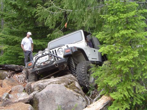 1989 Ford Bronco - A white Jeep Wrangler navigates a rocky trail, demonstrating off-road capability.