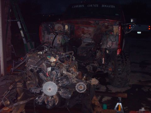 1982 Ford Bronco - A red SUV sits with its engine removed, revealing a complex mechanical interior under dark lighting.
