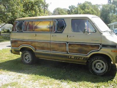 1978 Ford E250 - Custom 1978 Dodge van with wood paneling and painted windows parked on grass.
