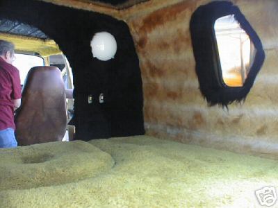 1978 Ford E250 - The custom interior of a van features shag carpeting and fur lining, with a view of the driver's seat and a unique hexagonal window.