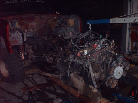 1982 Ford Bronco - The engine is being removed from the vehicle, with an engine hoist supporting its weight.