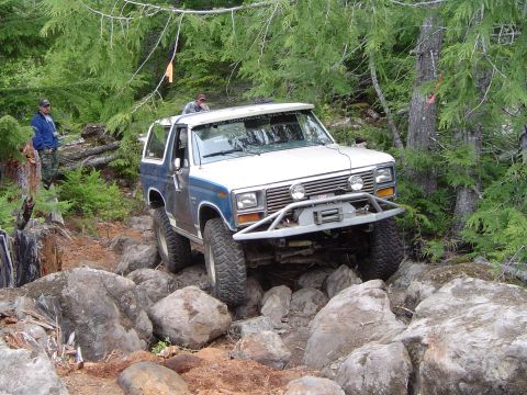 1989 Ford Bronco - A Ford Bronco tackles a challenging rocky terrain, with two people observing the off-road adventure.