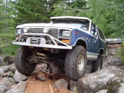 1989 Ford Bronco - This modified Ford Bronco navigates a rocky trail, its off-road capabilities evident.