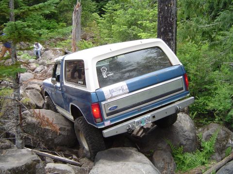 1989 Ford Bronco - Ford Bronco tackling difficult terrain on a rocky trail, showing its off-road capabilities.