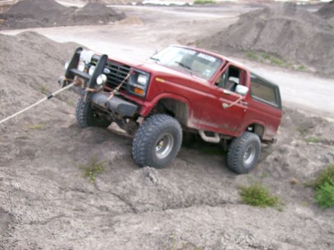 1982 Ford Bronco - This red Ford Bronco is equipped for off-road use and is seen climbing a dirt incline.