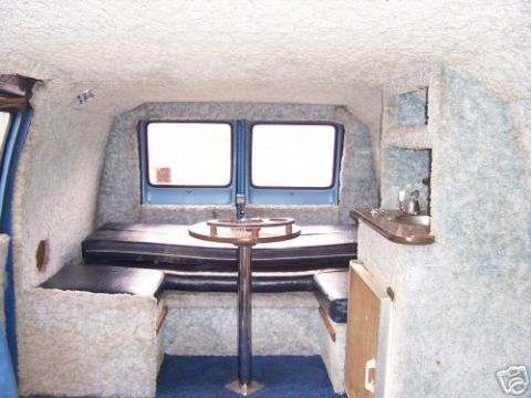 1978 Ford E250 - Custom van interior features upholstered seating, a table, and a small kitchenette area.