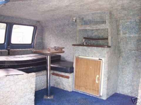1978 Ford E250 - This van's interior features a custom build with sleeping areas, a table, and a compact kitchen setup.