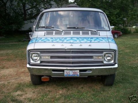 1978 Ford E250 - This van features a distinctive silver paint job with blue flame graphics on the front, seen from a straight-on perspective.