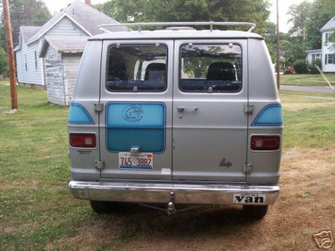 1978 Ford E250 - This van has a chrome bumper and a roof rack. A sticker on the bumper says 'It's a Van'.
