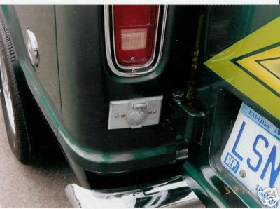 1978 Ford E250 - Rear view of a dark green 1978 Ford E250 van, showing its taillight, bumper, and an external power outlet.