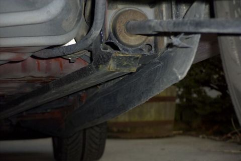 1997 Ford Taurus - Underbody view along the rocker of a car showing a black subframe connector welded to a bracket at the rear suspension mounting point, with…