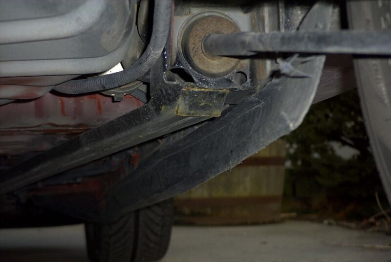 Underside view of a welded subframe connector at the rear suspension mount of a car