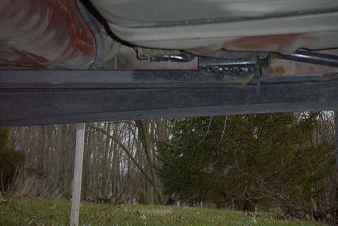 1997 Ford Taurus - Underside view of a light-colored car's rocker area shot from the ground, showing a welded-in subframe connector tied to the floor pan with…