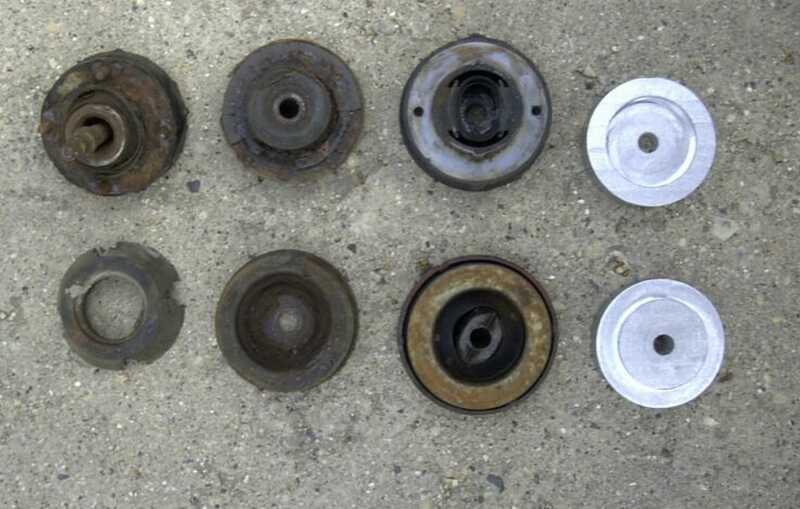 Used rusty strut mounts next to machined billet aluminum strut mount plates on concrete