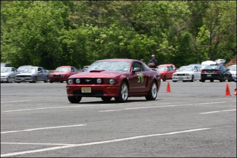 2001 Mercury Grand Marquis - A red Ford Mustang participates in an autocross event, with other vehicles lined up on the course.