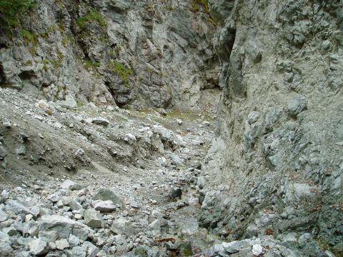 2000 Ford E350 - A rocky ravine with a dry creek bed winding through it, flanked by steep, gray rock faces.
