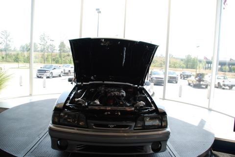1996 Ford Bronco - A black Ford Mustang is displayed with its hood open, revealing the engine and twin turbochargers.